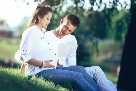 Photo for Future parents sitting on the grass in the Park on a Sunny day. - Royalty Free Image