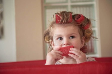 Téléchargez les photos : Petite fille bébé avec coiffure étrange et bigoudis - en image libre de droit
