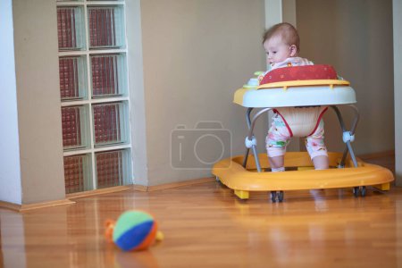 Photo for Baby learning to walk in walker - Royalty Free Image