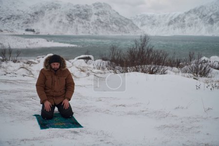 Téléchargez les photos : Voyageur musulman priant dans la neige froide journée d'hiver - en image libre de droit