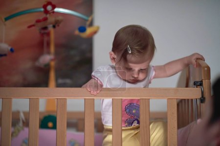Téléchargez les photos : Mignon petit bébé d'un an et faire les premiers pas au lit - en image libre de droit
