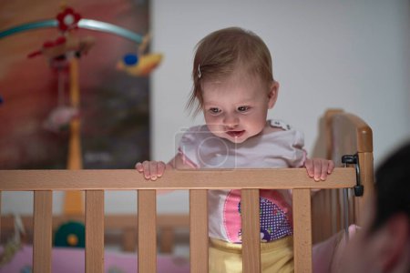 Téléchargez les photos : Mignon petit bébé d'un an et faire les premiers pas au lit - en image libre de droit