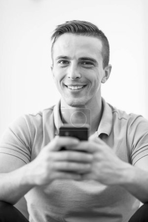 Téléchargez les photos : Jeune homme utilisant un téléphone portable à la maison - en image libre de droit