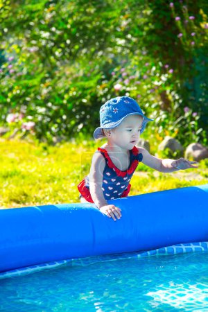 Téléchargez les photos : Petite fille jouant près de la piscine gonflable - en image libre de droit