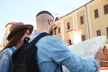 Téléchargez les photos : "Couple heureux marchant en plein air et tenant une carte
." - en image libre de droit