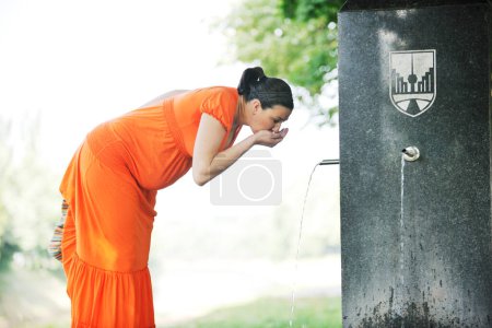 Téléchargez les photos : Femme enceinte dans une robe orange posant à l'extérieur, grossesse heureuse - en image libre de droit