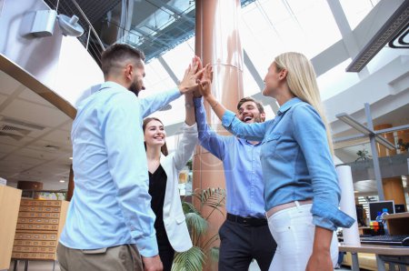 Téléchargez les photos : Jeunes gens heureux debout dans le bureau et donnant cinq hauts à leurs collègues
. - en image libre de droit