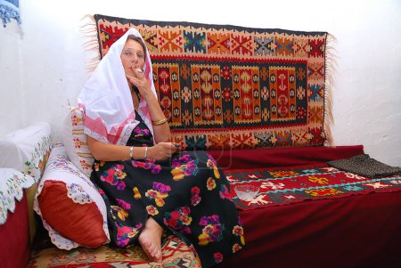 Foto de Mujer islámica madura sentada en casa y fumando - Imagen libre de derechos