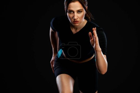 Foto de Sprinter y Runner. Mujer corriendo sobre el fondo negro. El concepto de un estilo de vida saludable y el deporte. Mujer en ropa deportiva
. - Imagen libre de derechos