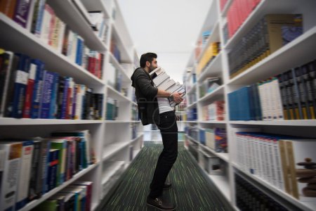 Téléchargez les photos : Étudiant tenant beaucoup de livres dans la bibliothèque de l'école - en image libre de droit