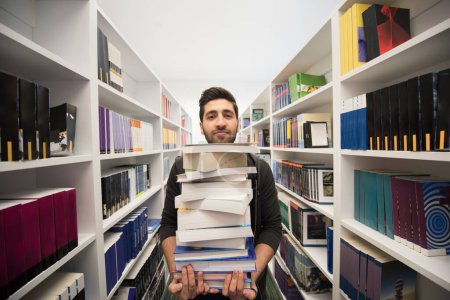 Photo for Student holding lot of books in school library - Royalty Free Image