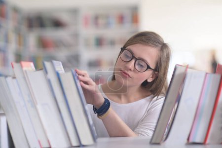 Foto de Retrato de una estudiante seleccionando un libro para leer en la biblioteca - Imagen libre de derechos