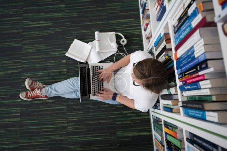 Téléchargez les photos : Étudiantes étudient à la bibliothèque, en utilisant une tablette et en recherchant des informations sur Internet - en image libre de droit