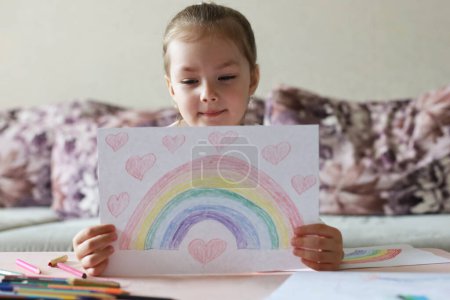 Photo for "Girl painting rainbow at home, a symbol of UK National Health Service (NHS). Thanks to the doctors for their work. Stay at home Social media campaign." - Royalty Free Image