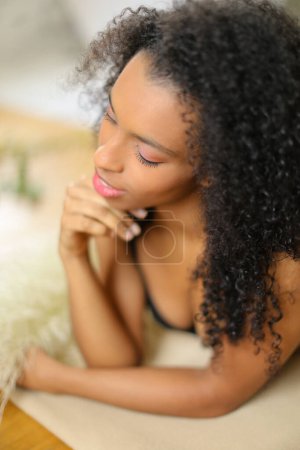 Téléchargez les photos : "Jeune femme noire couchée sur les coudes et portant un soutien-gorge." - en image libre de droit