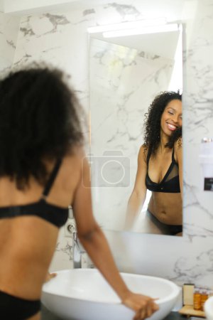 Foto de Volver ver negro feliz chica mirando espejo reflexión en cuarto de baño. - Imagen libre de derechos