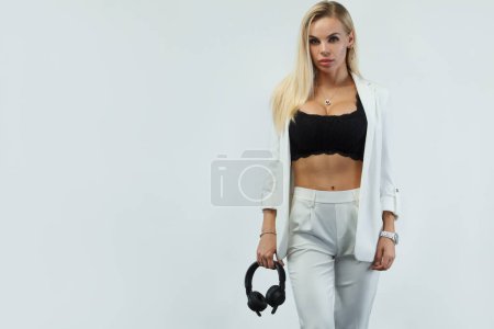 Foto de Hermosa sexy rubia DJ mujer sobre fondo blanco en estudio con auriculares - Imagen libre de derechos