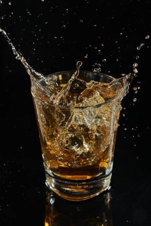 Photo for Glass of whiskey into which ice falls. frozen splashing drops - Royalty Free Image