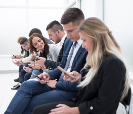 Téléchargez les photos : Jeunes employés regardant leurs écrans de smartphone - en image libre de droit