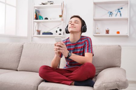 Foto de Adolescente disfrutando de la música en los auriculares en casa - Imagen libre de derechos