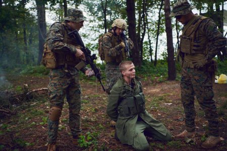 Téléchargez les photos : Interrogatoire de l'homme dans la forêt par des soldats - en image libre de droit