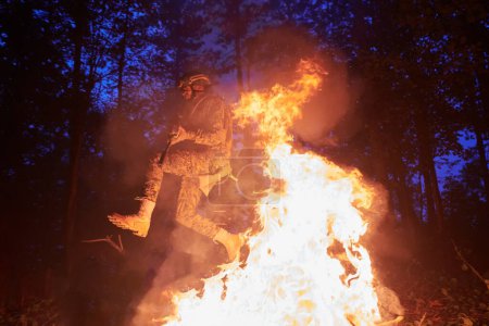 Téléchargez les photos : Soldat en action la nuit sautant par-dessus le feu - en image libre de droit