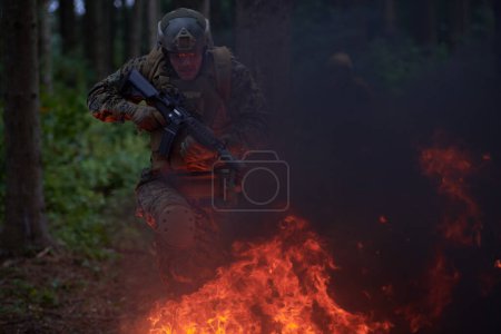 Téléchargez les photos : Soldat en action la nuit sautant par-dessus le feu - en image libre de droit