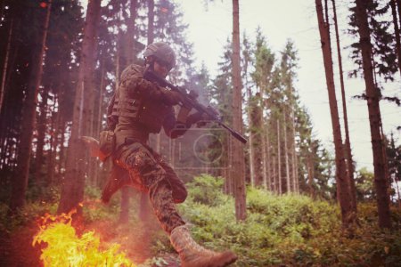 Photo for Soldier in Action at Night jumping over fire - Royalty Free Image