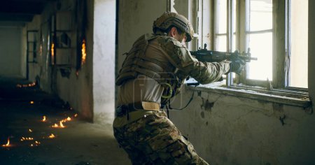 Téléchargez les photos : Soldat en action près de fenêtre changeant de magazine et prendre refuge - en image libre de droit
