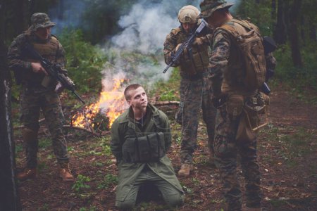 Foto de Interrogatorio del hombre en el bosque por soldados - Imagen libre de derechos