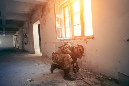 Téléchargez les photos : Soldat en action près d'une fenêtre changeant de magazine et se mettant à couvert - en image libre de droit