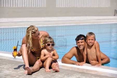 Téléchargez les photos : Heureux jeune famille avoir du plaisir dans la piscine - en image libre de droit