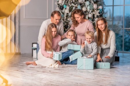 Foto de Gran familia feliz con muchos niños abriendo regalos bajo el árbol de Navidad en la víspera de Navidad - Imagen libre de derechos
