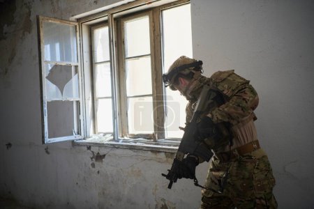 Photo for Soldier in action near window changing magazine and taking cover - Royalty Free Image