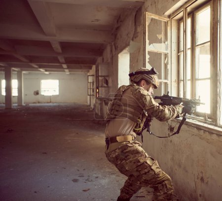 Photo for Soldier in action near window changing magazine and taking cover - Royalty Free Image