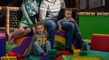 Téléchargez les photos : Les jeunes parents et les enfants qui s'amusent dans la salle de jeux pour enfants - en image libre de droit