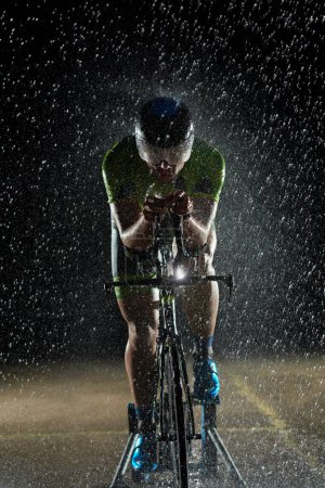 Foto de Triatlón atleta montar bicicleta rápido en la noche lluviosa - Imagen libre de derechos