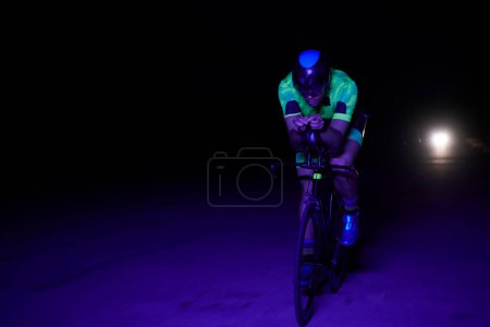 Photo for Triathlon athlete riding bike fast at night - Royalty Free Image