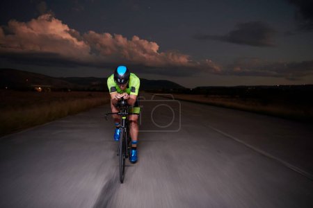 Foto de Triatlón atleta montar bicicleta rápido por la noche - Imagen libre de derechos