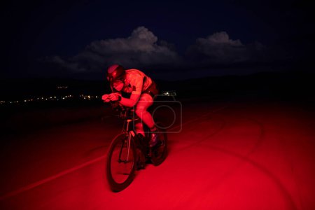 Photo for Triathlon athlete riding bike fast at night - Royalty Free Image