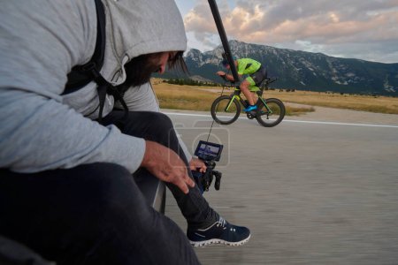 Photo for Cinematographer taking action shot of triathlon bike athlete - Royalty Free Image