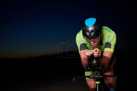 Téléchargez les photos : Triathlon athlète vélo d'équitation rapide la nuit - en image libre de droit