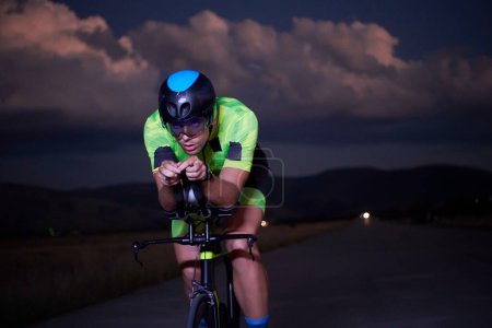 Téléchargez les photos : Triathlon athlète vélo d'équitation rapide la nuit - en image libre de droit