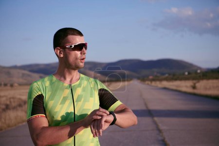 Foto de Atleta de triatlón descansando y estableciendo smartwatch - Imagen libre de derechos