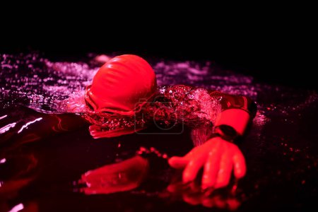 Téléchargez les photos : Véritable athlète de triathlon nageant dans la nuit noire - en image libre de droit