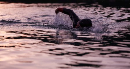 Foto de Atleta de triatlón nadando en el lago al amanecer usando traje de neopreno - Imagen libre de derechos