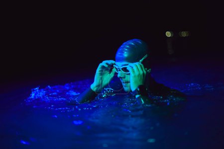 Photo for Authentic triathlete swimmer having a break during hard training on night neon gel light - Royalty Free Image
