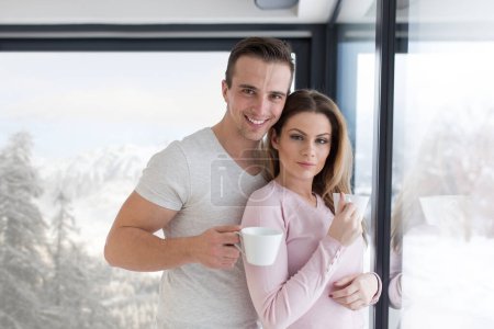 Téléchargez les photos : Jeune couple dégustant le café du matin par la fenêtre - en image libre de droit