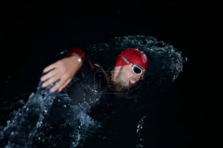Photo for Triathlon athlete swimming in dark night  wearing wetsuit - Royalty Free Image