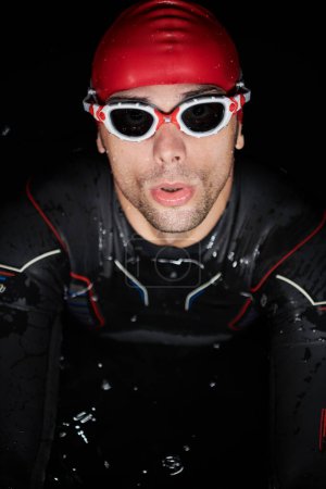 Photo for Authentic triathlete swimmer having a break during hard training on night - Royalty Free Image